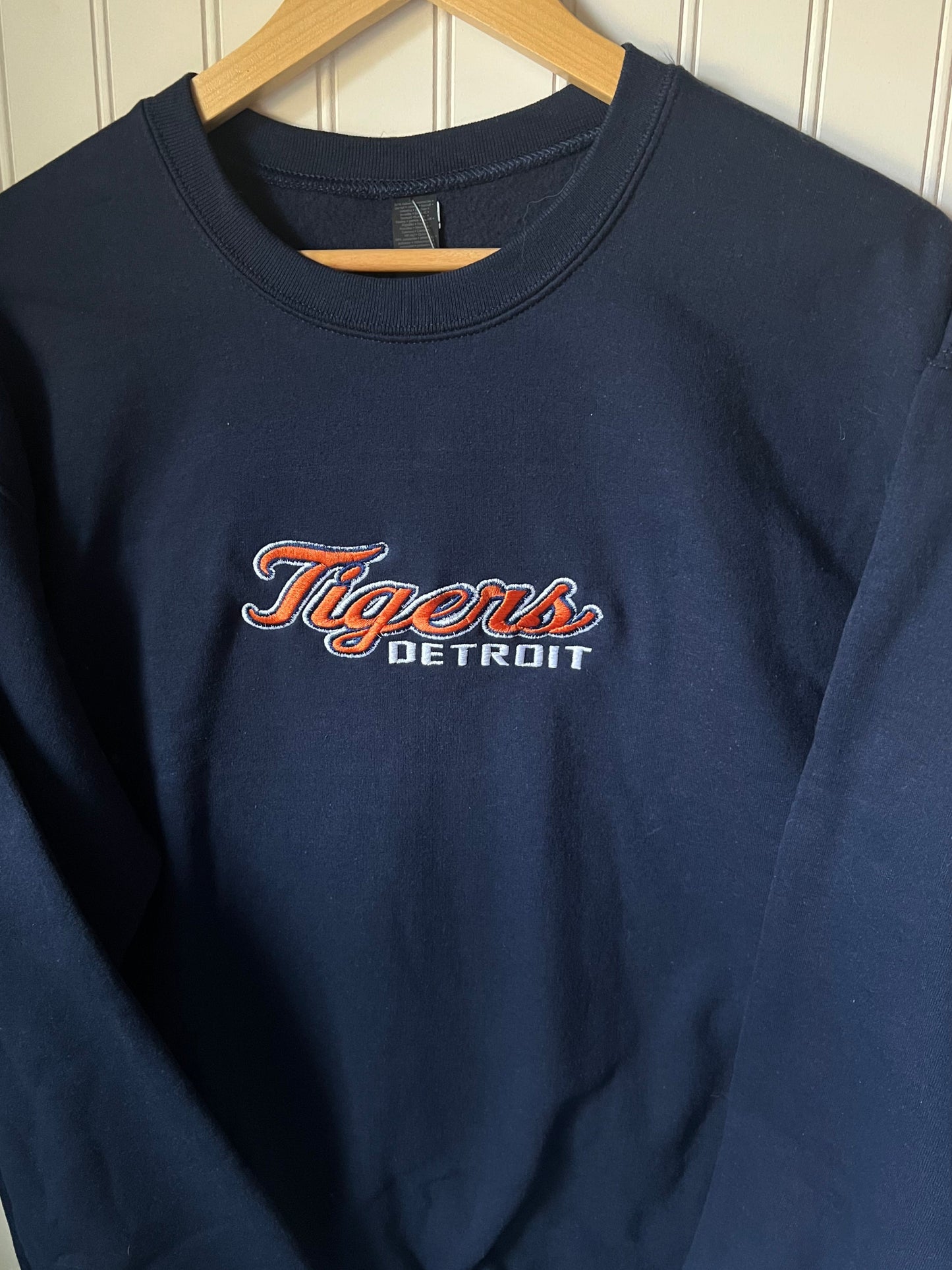 Navy blue t-shirt with 'Detroit Tigers' logo on a wooden hanger.